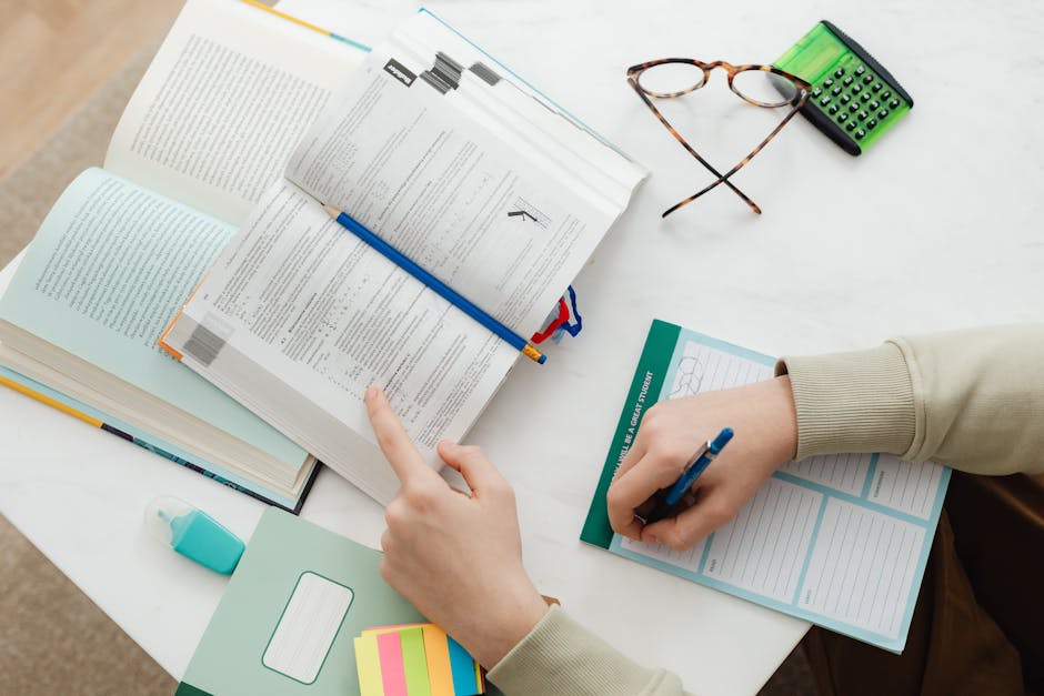 Top view of a student studying with open books, a calculator, and a notebook on a desk.