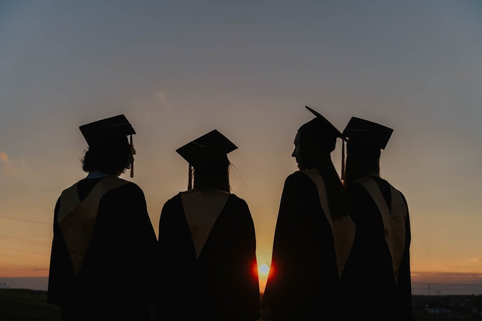 A group of graduates in caps and gowns silhouetted against a beautiful sunset, symbolizing achievement.